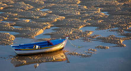 
fishing boat on dry sandbanks in Cacela-Velha in the Algarve, Portugal at sunset