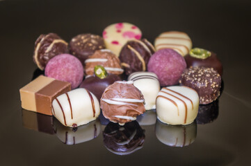 Luxurious mixed colored chocolate praline. Strawberry, coconut, vanilla and lemon truffles. Pralines designed in Belgium and arranged on table.