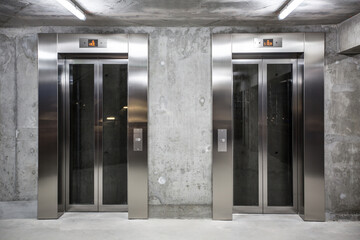 entrance to the building with two parallel lifts on raw walls