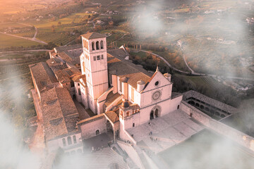 aerial view of the basilica of san francesco in the city of assisi umbria with fog - obrazy, fototapety, plakaty