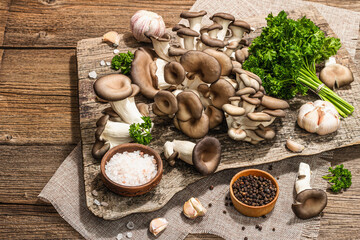 Oyster mushrooms ready for cooking. Fresh parsley, spices, garlic. Trendy hard light, dark shadows
