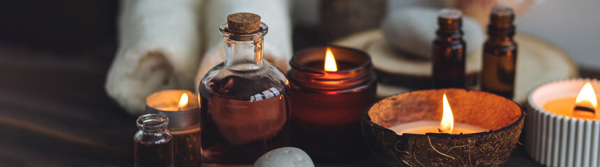 Concept of natural essential organic oils, Bali spa, beauty treatment, relax time. Atmosphere of relaxation, pleasure. Candles, towels, dark wooden background. Alternative oriental medicine. Banner