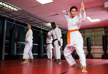 Asian woman in kimono is practicing different kicks at gym