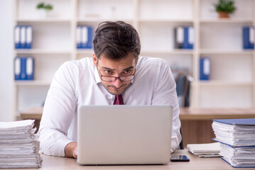 Young male employee and too much work at workplace