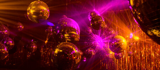 Fototapeta na wymiar disco background with disco balls in purple and gold lighting