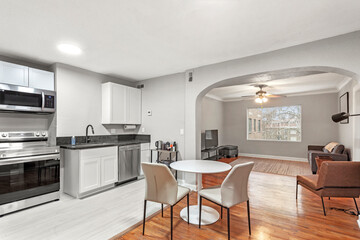 White apartment with wide open spaces, hardwood flooring and modern furniture. Used as a short term rental. 