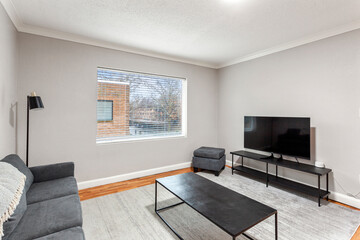 White apartment with wide open spaces, hardwood flooring and modern furniture. Used as a short term rental. 