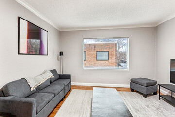 White apartment with wide open spaces, hardwood flooring and modern furniture. Used as a short term rental. 