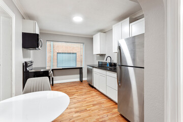 White apartment with wide open spaces, hardwood flooring and modern furniture. Used as a short term rental. 