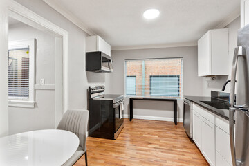White apartment with wide open spaces, hardwood flooring and modern furniture. Used as a short term rental. 