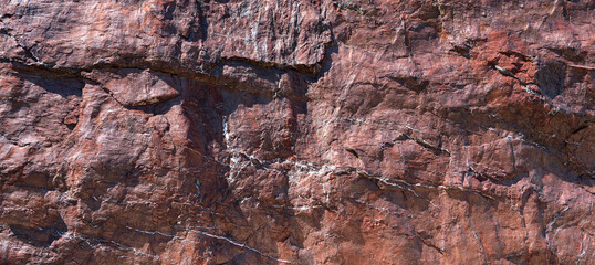 Grobe Oberfläche von einem rotbraunen Felsen in Nahaufnahme, mit abstrakten weißen Linien durchzogen
