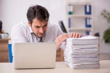 Young male employee unhappy with excessive work in the office