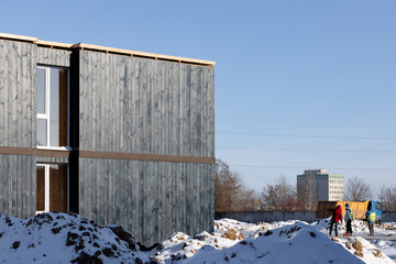 Wooden facade of a detached modular house with windows on the background of construction