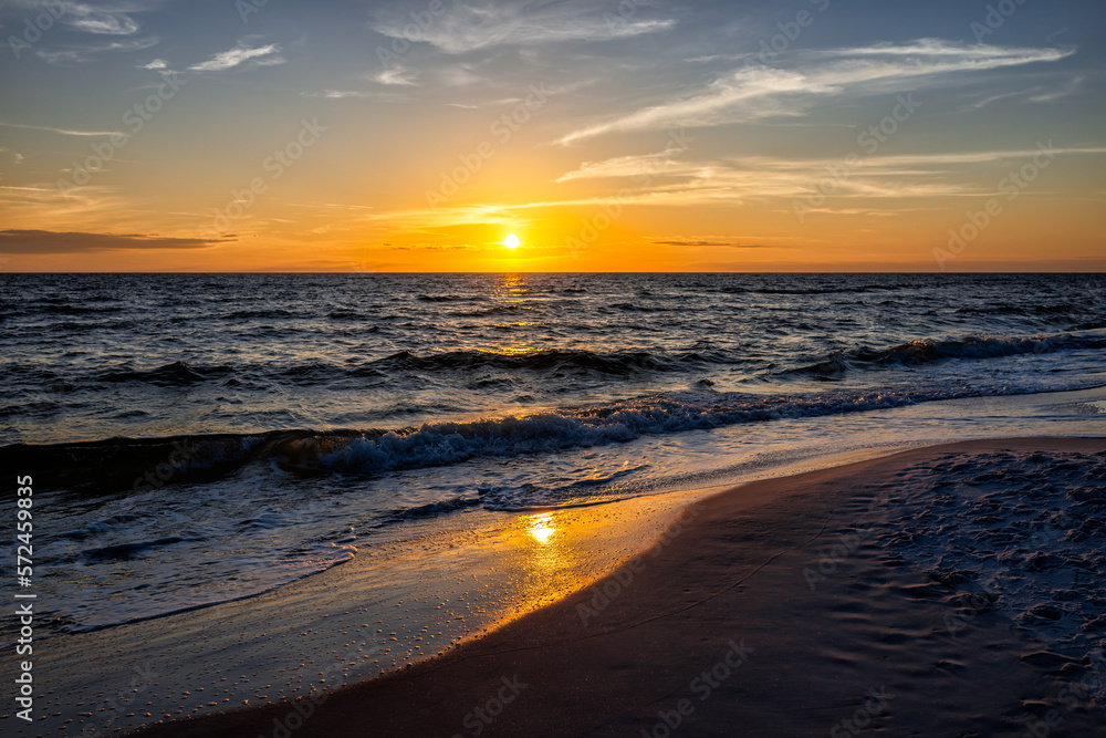 Wall mural Colorful sunset dusk with seascape horizon of sun setting in Gulf of Mexico sea ocean coast with water waves in Seaside Santa Rosa Beach, Florida panhandle and reflection of path