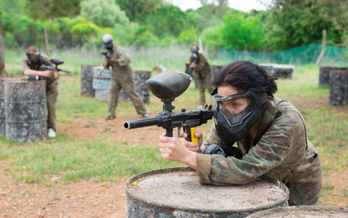 Excited male and female paintball players in protective uniform aiming and shooting with guns