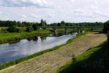 Fototapeta na wymiar Latvian summer nature, view of the river and bridge, trees and city