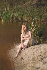 Girl in dress sitting near lake