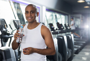 Positive man with bottle of water in a sports club