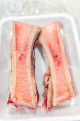 Raw uncooked beef marrow bones for roasting macro closeup with texture of pink red fat on plastic tray and nobody as trendy food