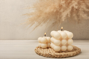 Soy wax bubble candle on a textured table. Interior decor with handmade burning candle and dried...