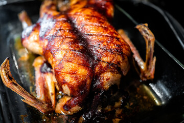 Whole roasted duck poultry bird closeup with score marks on in glass pan for baking with crispy brown golden skin macro with texture