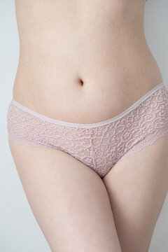 Product photo of a pair of pink lace cheeky  panty. The model has a natural body and has pale skin.