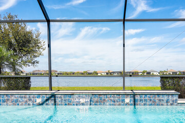 Fototapeta na wymiar Modern contemporary home screened glass lanai private pool spa with view of tropical lake in Florida with blue water in clean house