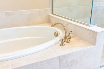 Modern white plain clean bathroom and closeup of bathtub with shower and tiles in model staging house, home or apartment