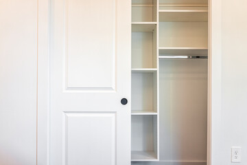 Walk-in closet shelves with sliding door in modern minimalist white style with bright light in...