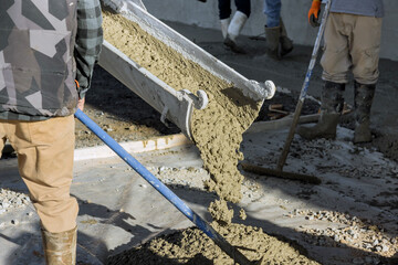 Concrete mixing truck pours out concrete for pavement surrounding new home © ungvar