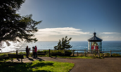 A couple of people using a spyglass and enjoying the view next to the Cape Meares lighthouse