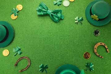 St Patricks Day frame of shamrocks, gold coins and leprechaun hat over a glittery green background