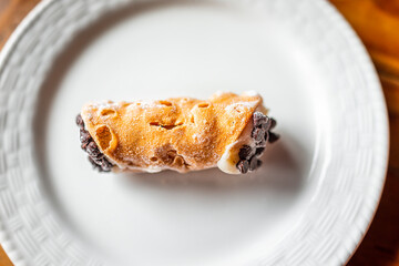 Italian cannolo one pastry dessert flat top closeup on white plate macro with texture of yellow...