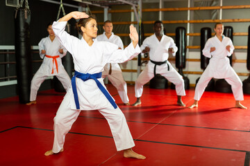 Fototapeta premium Woman in kimono fighting stance at karate training