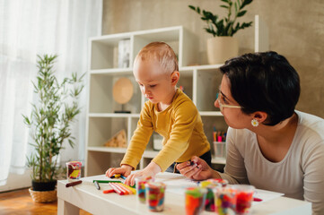 Mother and son drawing with crayons at home and creating art