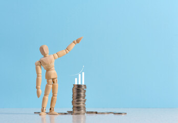 Wooden mannequin and a stack of coins on a blue background