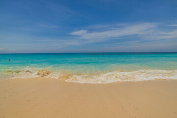 Beautiful view of turquoise water of Atlantic Ocean with rolling waves on sandy beach of Eagle Beach. Aruba island.