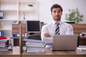 Fototapeta na wymiar Young male employee unhappy with excessive work at workplace