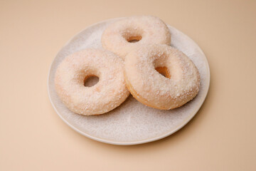 Coconut donuts in a plate on a beige background