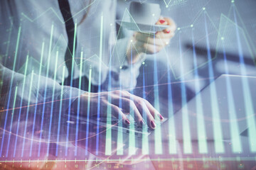 Double exposure of businesswoman hands typing on computer and financial graph hologram drawing. Stock market analysis concept.