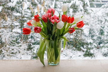 Fototapeta na wymiar A bouquet of tulips on the windowsill in winter