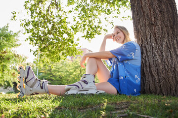 woman sitting in a park on inline skates. the sun is shining behind her.