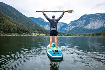 Man Paddling in an Alpine Lake, Enjoying the Mountain Scenery, Inflatable SUP Board Adventure