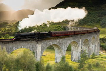 A steam train crossing the Glenfinnan viaduct in the Scottish Highlands made famous by the Harry Potter movies. The Jacobite steam train crossing the bridge with steam in Scotland United Kingdom