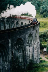 Papier Peint photo autocollant Viaduc de Glenfinnan A steam train crossing the Glenfinnan viaduct in the Scottish Highlands made famous by the Harry Potter movies. The Jacobite steam train crossing the bridge with steam in Scotland United Kingdom