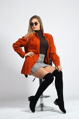 Young woman in the studio poses sitting on a chair, on a white background