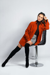 Young woman in the studio poses sitting on a chair, on a white background