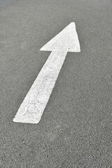 White painted arrow pointing forward on an asphalt road; a symbol of psychological states of mind.