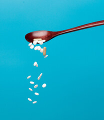 Daily pill drug medicine falling down float in spoon. Many kind of drugs pills medicines to help patient fly to senior. Mixed combination Drug pill medicine Medical over blue background isolated