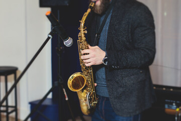 Naklejka premium Concert view of saxophonist, a saxophone sax player with vocalist and musical band during jazz orchestra show performing music on stage in the scene lights